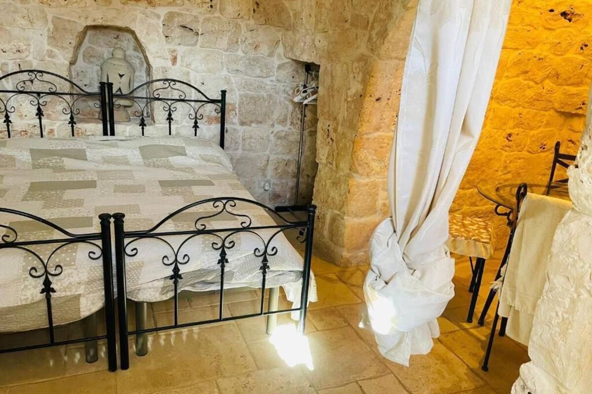 Una habitación con paredes de piedra, una cama, una silla y una mesa.