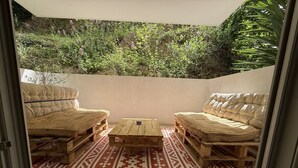 Eine gemütliche Terrasse mit zwei gepolsterten Sofas, einem Holztisch und einem gemusterten Teppich.