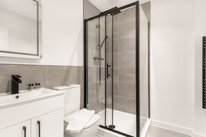 A modern bathroom with a glass-enclosed shower, a white sink, and a toilet. - Bright & Contemporary 1 Bed Apartment in Leeds (Leeds)