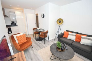 Un salon moderne comprenant un canapé, des fauteuils, une table basse et un coin repas avec une table et des chaises.