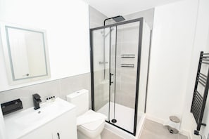A modern bathroom with a glass-enclosed shower, a white sink, and a toilet. - Bright & Contemporary 1 Bed Apartment in Leeds (Leeds)