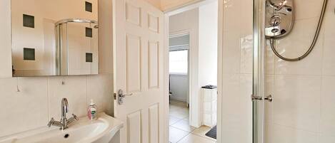 Baño con lavamanos, espejo y ducha.