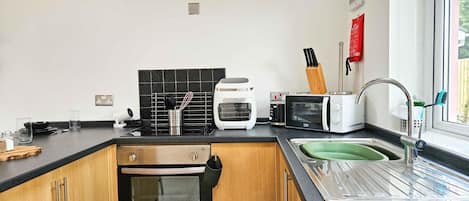 A modern kitchen with a built-in oven, a toaster, a kettle, and a sink.