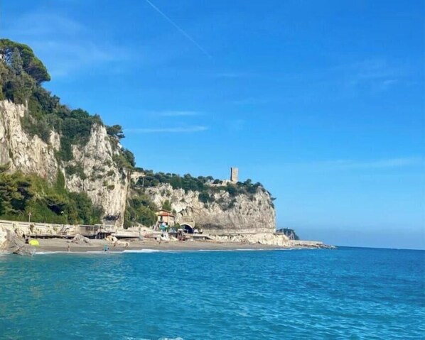 Un paysage côtier avec une falaise, une plage et un phare.