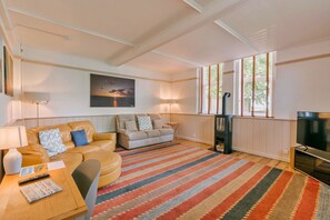 A living room with a sofa, a TV, a lamp, a rug, and a painting on the wall. - Finest Retreats | Wallingbrook Lodge (Chulmleigh)