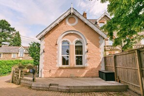 A building with a pitched roof, a central arched window, and a wooden fence. - Finest Retreats | Wallingbrook Lodge (Chulmleigh)