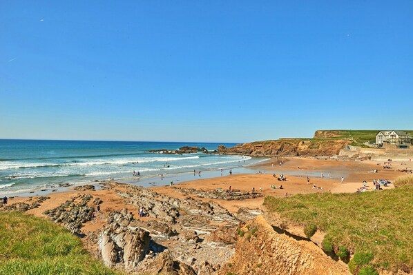 A coastal beach with rocky terrain and a clear blue sky. - Bude Bolthole (Bude)