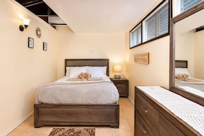 A bedroom with a bed, bedside table, lamp, mirror, and a wall sign. - Tropical SeaSide Villa (Aguada)