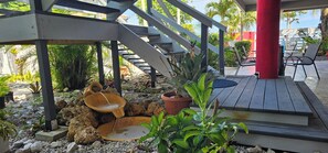 A wooden deck with a stone water feature, potted plants, and a staircase leading to an upper level. - Tropical SeaSide Villa (Aguada)