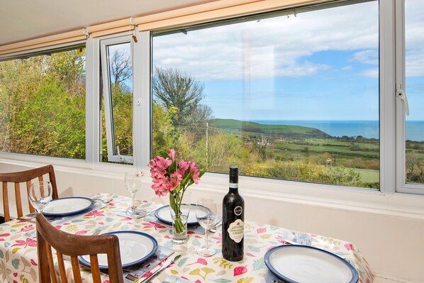 A dining table with plates, a wine bottle, and a vase of flowers. - Arfron (Dinas Cross)