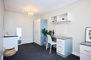 A modern, well-lit room with a desk, chair, and shelving unit.