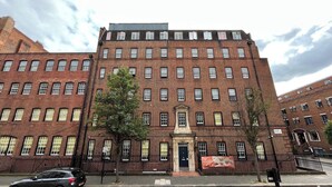 Un edificio de ladrillo rojo con múltiples ventanas y una entrada central.