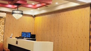 A reception area with a reception desk, a chandelier, and a wooden panel wall. - Hotel Crystal Inn (Lucknow)