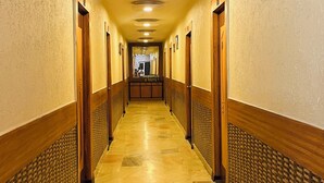 A hotel hallway with a marble floor, wooden paneling, and doors on both sides. - Hotel Crystal Inn (Lucknow)