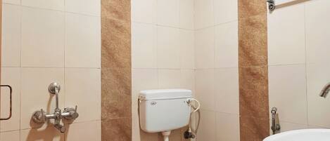 A bathroom with a toilet, a sink, a red bucket, and a showerhead.