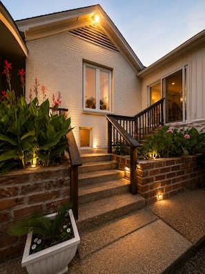 Una casa con fachada de ladrillo, una escalera de madera y una entrada bien iluminada.