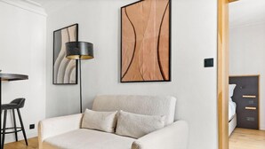 Et moderne værelse med en hvid sofa, en gulvlampe og abstrakt vægkunst.