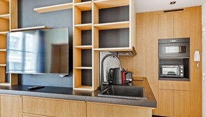 Eine moderne Küche mit Flachbildfernseher, Backofen und Spüle.