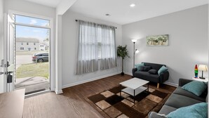 En moderne stue med sofa, sofabord, lampe og et maleri på væggen.