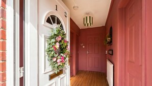 Un pasillo con una puerta blanca, una pared roja y un suelo de madera.
