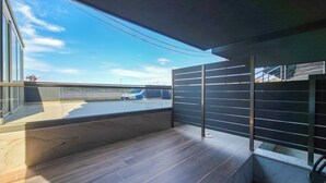 Un balcó modern amb vista a una zona d'aparcament i un cel clar.