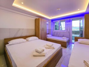 Een hotelkamer met twee bedden, een badkamer en een balkon met uitzicht.