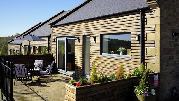 A wooden cabin with a patio, outdoor seating, and a garden. - 1 The Old Stables is a rural cottage with scenic countryside views. (Knitsley)
