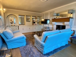 A living room with a sofa, a television, a fireplace, and a mirror. - Country house - Sleeps 8 (Jublains)