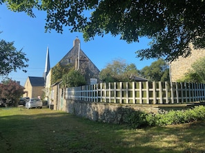 A stone church with a tall spire, a white picket fence, and a parked car in front. - Country house - Sleeps 8 (Jublains)