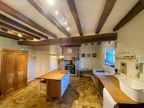 A kitchen with a wooden table, a brick wall, and a sink. - Country house - Sleeps 8 (Jublains)