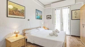 Een slaapkamer met een bed, nachtkastjes, een raam met gordijnen en decoratie aan de muur.
