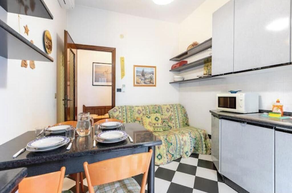 Una cocina compacta con una mesa de comedor lista para cuatro personas, un microondas y un sofá estampado.