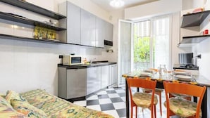 Een kleine keuken met een eethoek, een bed en uitzicht door een glazen deur.