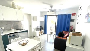 Een compacte leefruimte met kitchenette, eethoek en een bank.