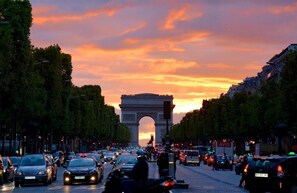 Eine belebte Straße, im Hintergrund der Arc de Triomphe.