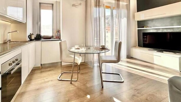 Una cocina moderna con comedor, televisor y ventana con cortinas.
