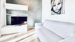 Una sala de estar moderna con un televisor de pantalla plana, un sofá blanco y un diseño minimalista.