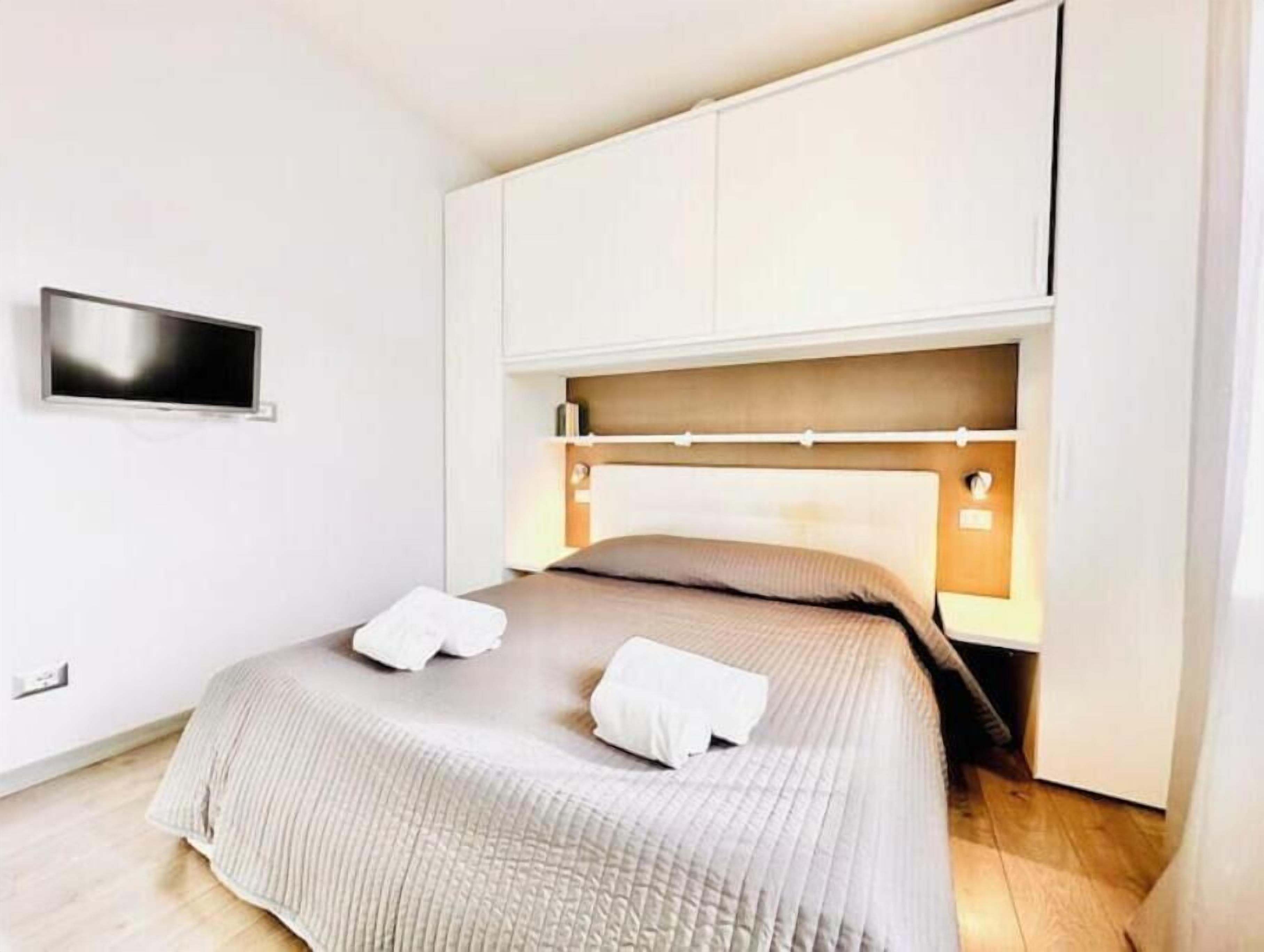 A bedroom with a bed, a TV mounted on the wall, and a built-in wardrobe.