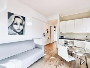 Ein modernes Wohnzimmer mit einer Couch, einem Glastisch und weißen Schränken.