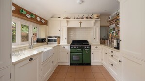 A kitchen with white cabinets, a green oven, and a microwave.