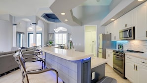 A modern kitchen with a central island, bar stools, a built-in microwave, and a large oven. - Cape Coral Lakefront Living! Home w/ Pool, Lanai (Cape Coral)