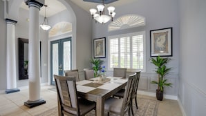 A dining room with a large table, chairs, a chandelier, and framed artwork on the walls. - Cape Coral Lakefront Living! Home w/ Pool, Lanai (Cape Coral)