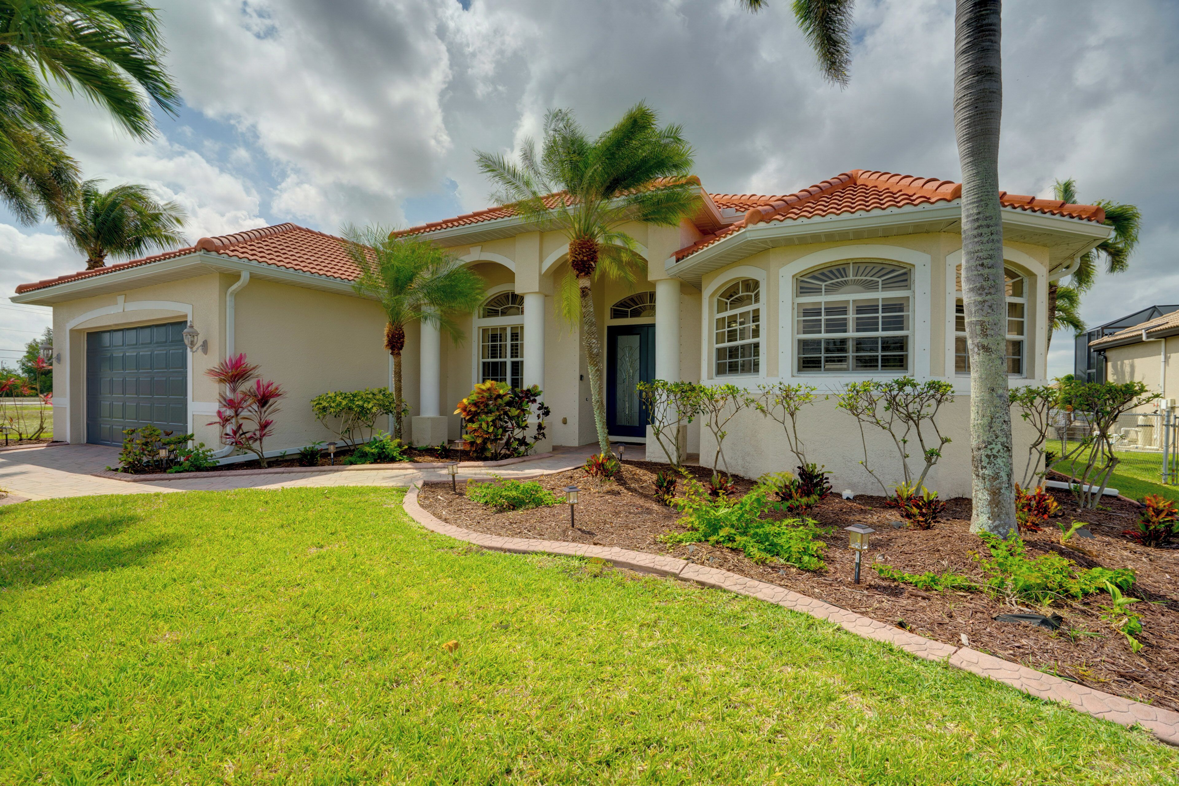 A two-story house with a red-tiled roof, a garage, and a well-maintained lawn.