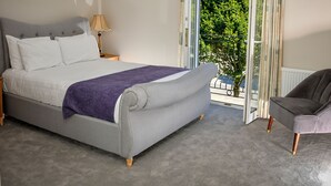 A bedroom with a bed, a nightstand, a chair, and a view of greenery outside.