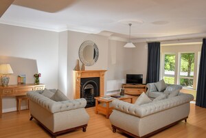 A living room with a fireplace, two sofas, a coffee table, a TV, and a desk with a lamp.
