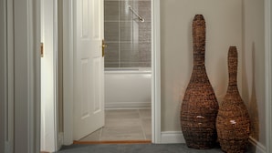 A hallway with a white door, a handrail, and two wicker vases.