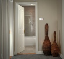 A hallway with a white door, a handrail, and two wicker vases.