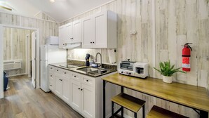 Una cocina con armarios blancos, un microondas, un tostador y un extintor.