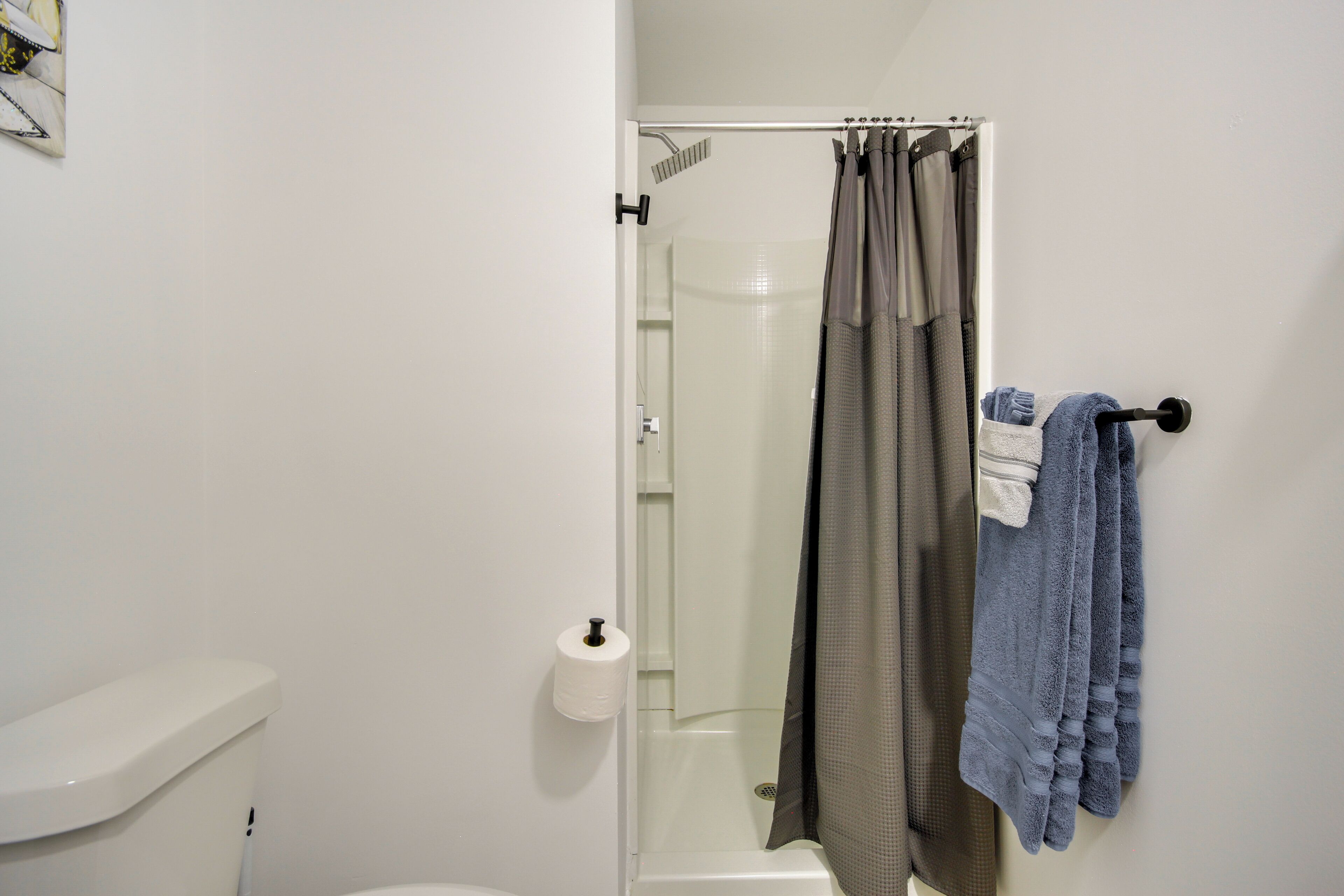 A bathroom with a toilet, a shower with a glass door, and a towel rack with towels.