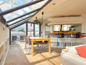 A modern interior with a dining area, a sofa, a bookshelf, and a skylight. - Attico Torlonia - Terrazzo in centro città (Roma)